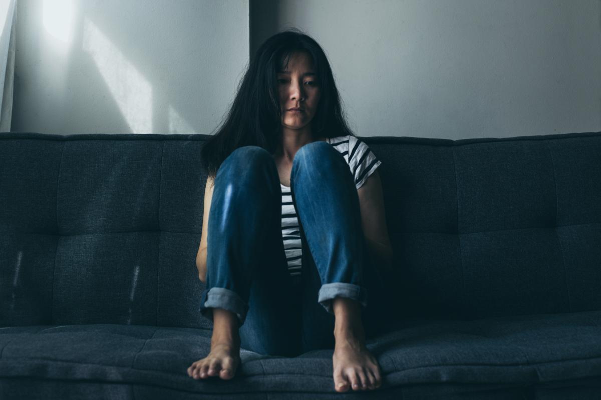 a woman sits on a couch and wonders about the dangers of opiates